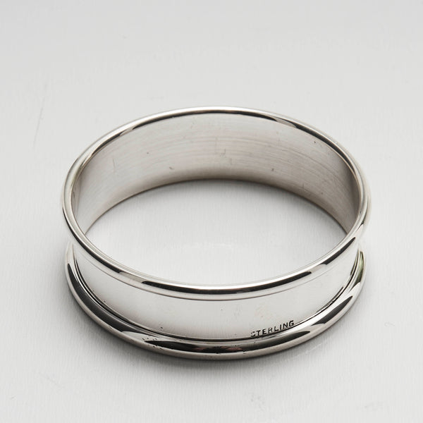 A sterling silver napkin ring with a smooth, polished finish. Stamped  'STERLING'